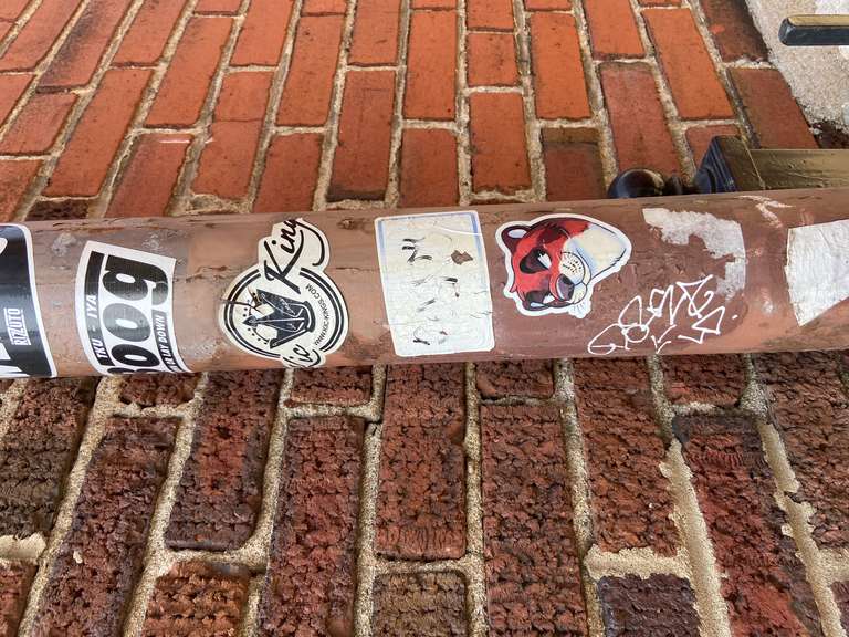 A pipe in an alley with stickers on it