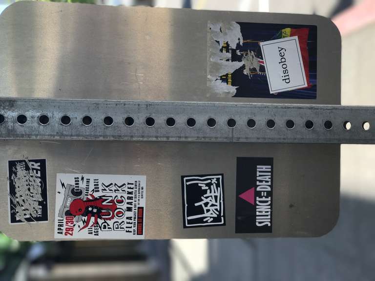 Several stickers. Punk Rock Flea Market, Silence Equals Death, Blink to the Future, a Disobey sticker placed over a donald trump sticker